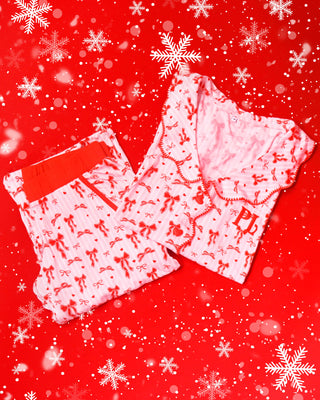 Pair of pink and white striped pyjamas with red festive bow designs set on a red background with snowflakes