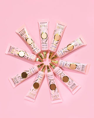 Multiple tubes of P.Louise eye base  primer arranged in a wheel-like pattern on a pink background.
