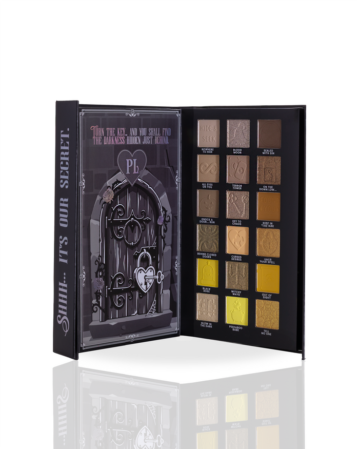 An open makeup palette with a gothic theme, featuring a black cover with a dark door illustration and text reading 'Sssh... It's Our Secret'. The right side shows multiple square eyeshadow pans in neutral and gold shades with printed names beneath them.