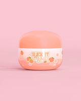 Jar of P. Louise Slick It To Me Peach Melting Body Balm with pink background